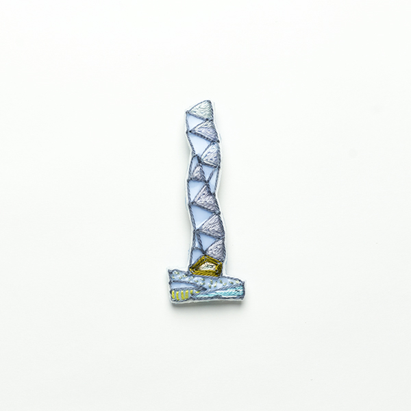 B34 タワーブローチ〈ペールミスト/シルバー×ダークグレー〉<br>制作者:Kimiko Sekine<br>サイズ:7cm×2.5cm<br>素材:布、PPシート、フェルト、刺繍糸、ブローチピン<br><br>水戸芸術館のタワーはいつも変わらず佇んでいますが、いつも違ってみえます。このブローチは展望室からきらめく大洗海岸を見やるタワーをイメージして作りました。