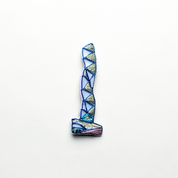 B3 タワーブローチ〈シルバー×ブルー〉<br>制作者:Kimiko Sekine<br>サイズ:7cm×2.5cm<br>素材:布、PPシート、フェルト、刺繍糸、ブローチピン<br><br>水戸芸術館のタワーはいつも変わらず佇んでいますが、いつも違ってみえます。このブローチは青空を映し込んだタワーをイメージして作りました。