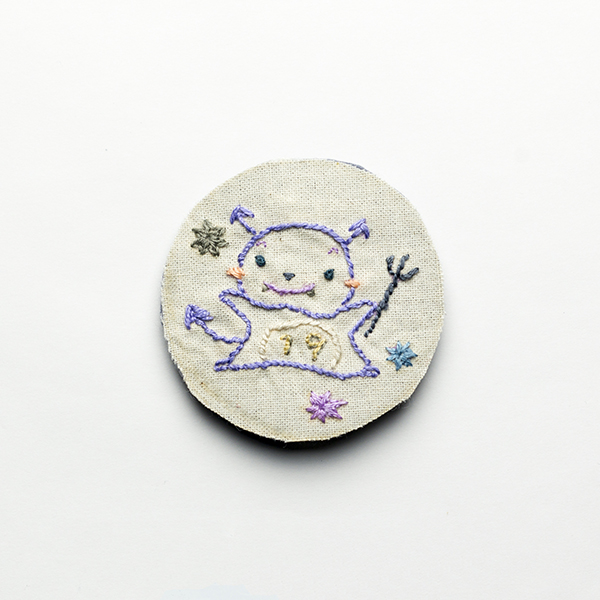 B14 コビッドくん<br>制作者:わたげ<br>サイズ:5cm×5cm<br>素材:刺繍糸、布、フェルト、ブローチピン<br><br>青山さんとの白衣の寄せ縫いで、ある文脈の中でコビッドくんを登場させました。コロナウィルスをゆるキャラのようにデザインしました。 後先考えずに、コビットくんだけを抜粋してブローチにしましたが、制作しながら恐ろしくなってきました。コロナで身近な人を亡くされた方や、ご家族やご本人が陽性になったがために、嫌がらせにあった方々からすると、コロナのブローチなんて身に着けたくないでしょう。むしろ、コロナを冗談にしたり、ポップに扱うことは批判を受けるでしょう。withコロナってなんでしょう?このブローチを手にとってくれる方はどんな方なのでしょう? 私とは違う受け取り方をしてくれる人の考えを聞きたい。そして、私の今の葛藤を記録したいという思いから、販売することに決めました。