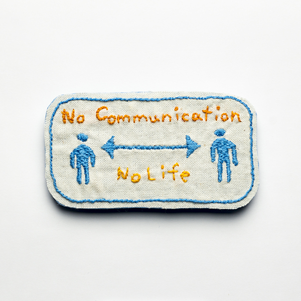 B17 No Communication No Life<br>制作者:わたげ<br>サイズ:4.3cm×7.6cm<br>素材:刺繍糸、布、フェルト、ブローチピン<br><br>劇場勤務でも使うようになった「ソーシャルディスタンス」のサイン。 それでも私たちのコミュニケーションは止められない。