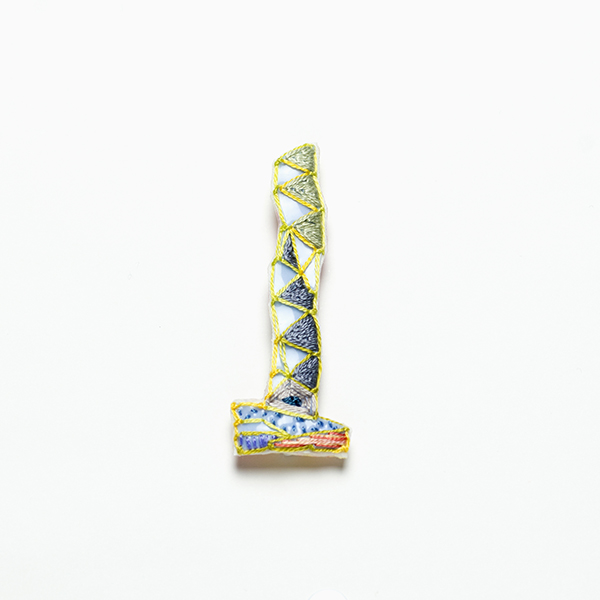 B31 タワーブローチ〈ミスとグリーン/スモークグレー×イエロー〉<br>制作者:Kimiko Sekine<br>サイズ:7cm×2.5cm<br>素材:布、PPシート、フェルト、刺繍糸、ブローチピン<br><br>水戸芸術館のタワーはいつも変わらず佇んでいますが、いつも違ってみえます。このブローチは早朝の穏やかな光に包まれているタワーをイメージして作りました。