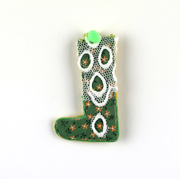 B577 もう片方どこいった?<br>制作者:Ki<br>サイズ:6.6cm×3.1cm<br>素材: 布、フェルト、刺繡糸、レースリボン、ポンポン玉、ビーズ、ブローチピン<br><br>初めは大切に履いていたのに、気がつくと失くしている。それが、靴下だったりピアスだったり。失う事に焦点を当てたブローチです。
