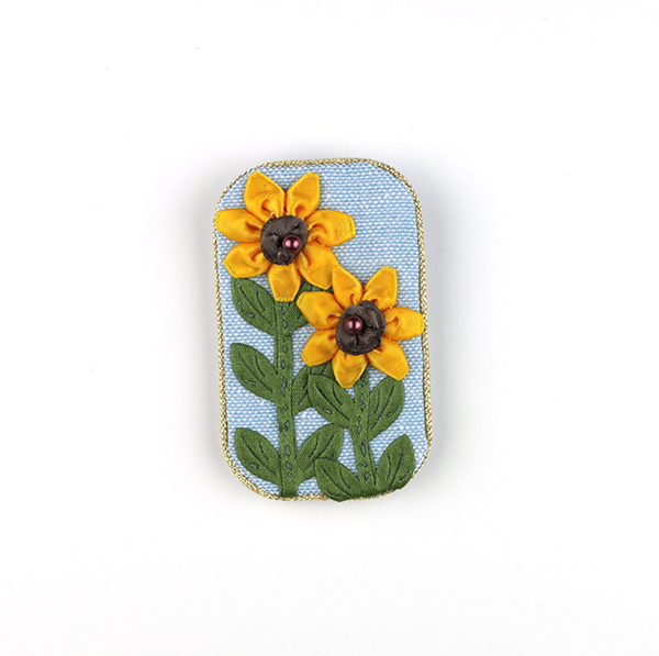 B589 ライトブルー ひまわり長方形(タテ)<br>制作者:CHAi<br>サイズ:7cm×4cm<br>素材:布、リボン、アジアンコード、ビーズ、ブローチピン<br><br>リボンで夏の花が咲きました