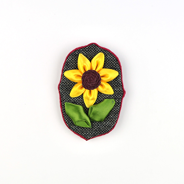 B590 黒系 ひまわりオーバル変形(タテ)<br>制作者:CHAi<br>サイズ:7cm×5cm<br>素材:布、リボン、アジアンコード、ブローチピン<br><br>リボンで夏の花が咲きました