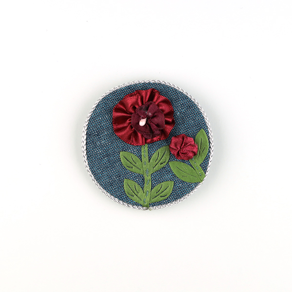 B591 赤い花(ブルー丸型)<br>制作者:CHAi<br>サイズ:6cm×6cm<br>素材:布、リボン、アジアンコード、ペップ、ブローチピン<br><br>リボンの花が咲きました