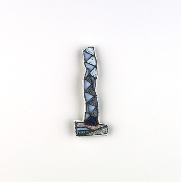 B592 タワーブローチ〈ペールミスト/スモークグレー×スモークグレー〉<br>制作者:Kimiko Sekine<br>サイズ:7cm×2.5cm<br>素材:布、PPシート、フェルト、刺繍糸、ブローチピン<br><br>水戸芸術館のタワーはいつも変わらず佇んでいますが、いつも違ってみえます。このブローチは、夏の匂いが立ち上がる広場で、がっしりとたたずむ水戸芸術館のタワーをイメージして作りました。
