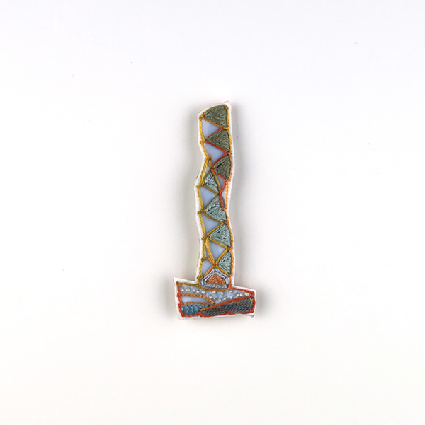 B594 タワーブローチ〈オーキッドグレー/スターライトブルー×マリーゴールド〉<br>制作者:Kimiko Sekine<br>サイズ:7cm×2.5cm<br>素材:布、PPシート、フェルト、刺繍糸、ブローチピン<br><br>水戸芸術館のタワーはいつも変わらず佇んでいますが、いつも違ってみえます。このブローチは、マリーゴールド色の陽に照らされて輝く水戸芸術館のタワーをイメージして作りました。