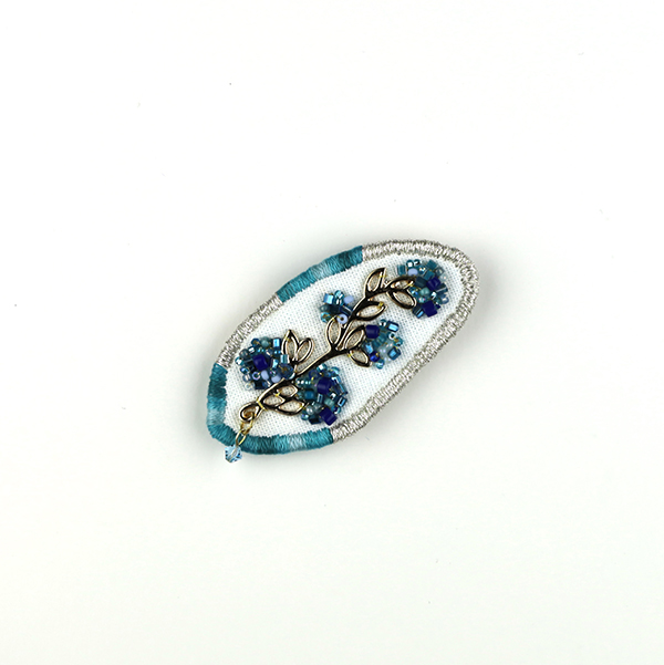 B599 集合体(アクアマリン)<br>制作者:Sukesan<br>サイズ:4cm×6cm<br>素材:布、フェルト、刺繍糸、メタルパーツ、ビーズ、スワロフスキー(アクアマリン)、合成皮革、ブローチピン<br><br>植物も人間社会もいろいろなモノ達が集まって造られているんですよね。