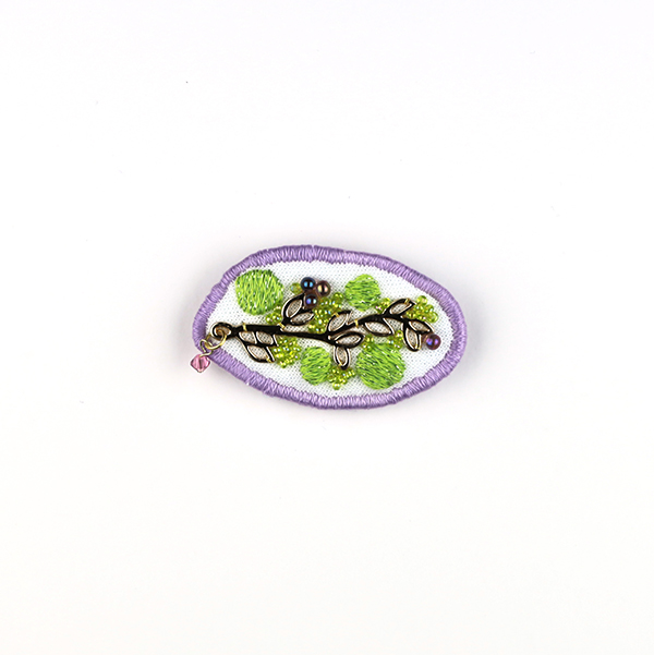 B601 集合体(ローズ)<br>制作者:Sukesan<br>サイズ:3.7cm×5cm<br>素材:布、フェルト、刺繍糸、メタルパーツ、ビーズ、チェコビーズ、スワロフスキー(ローズ)、合成皮革、ブローチピン<br><br>植物も人間社会もいろいろなモノ達が集まって造られているんですよね。
