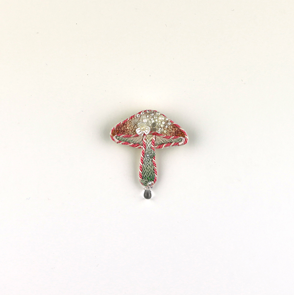 B633 土に還る(蜜)<br>制作者:itoco<br>サイズ:4.3cm×3.6cm<br>素材: フェルト、刺繍糸、組紐、レース糸、ビーズ、淡水パール、合成皮革、ブローチピン<br><br>花の蜜の甘い香りが漂ってきそうなキノコです。