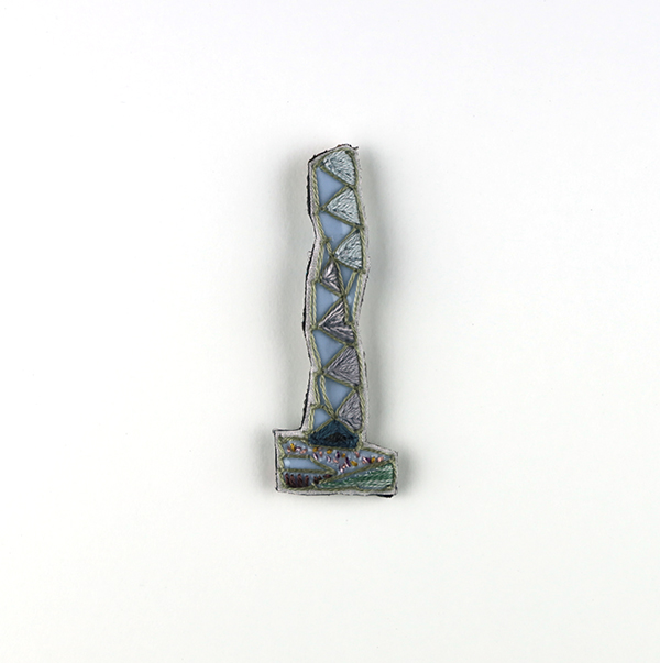 B645 タワーブローチ〈ペールブルー/ピジョン×ミストグリーン〉<br>制作者:Kimiko Sekine<br>サイズ:7cm×2.5cm<br>素材:布、PPシート、フェルト、刺繍糸、ブローチピン<br><br>水戸芸術館のタワーはいつも変わらず佇んでいますが、いつも違ってみえます。このブローチは、立ち昇る土の香りと揺れる夏の草花をそっと見守る水戸芸術館のタワーをイメージして作りました。