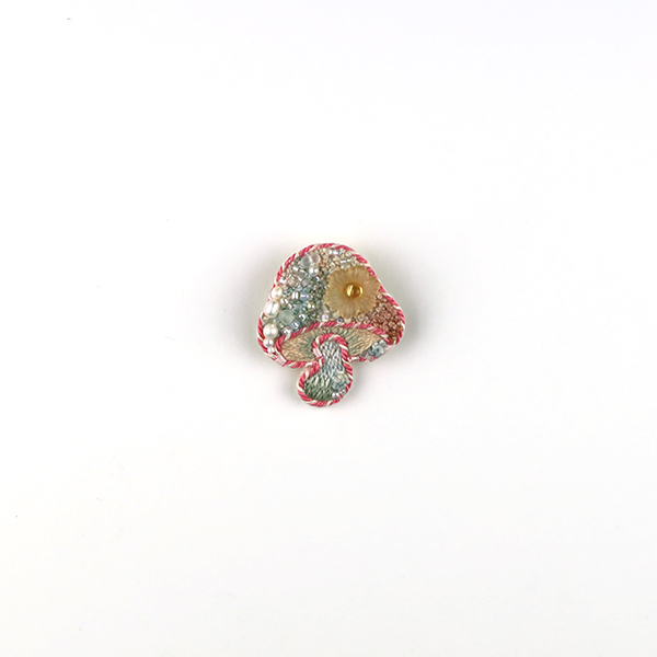 B668 土に還る‶紅葉″<br>制作者:itoco<br>サイズ:3.5cm×3.1cm<br>素材: フェルト、刺繍糸、組紐、ビーズ、淡水パール、プラスチックパーツ、合成皮革、ブローチピン<br><br>新緑から赤く色づき始める紅葉の季節を表したきのこです。