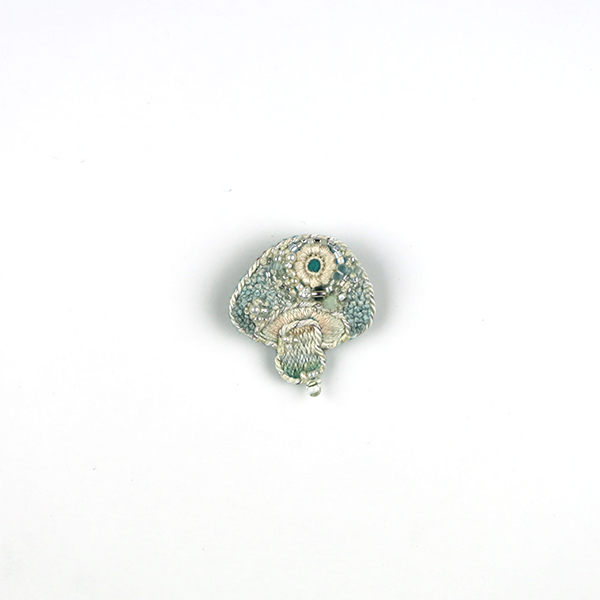 B755 土に還る‶霰“(あられ)<br>制作者:itoco<br>サイズ:3.5cm×3cm<br>素材: フェルト、刺繍糸、組紐、レース糸、ビーズ、淡水パール、合成皮革、ブローチピン<br><br>霰のような氷の粒をちりばめたようなキノコです。